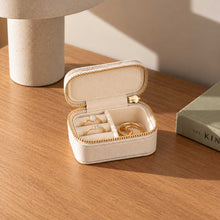 Charger l'image dans la galerie, Mini boîte à bijoux de voyage beige ouverte avec bagues dorées sur une console en bois