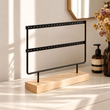 Charger l'image dans la galerie, Porte-boucles d'oreilles noir à deux rangées, avec socle en bois naturel, posé sur une commode blanche