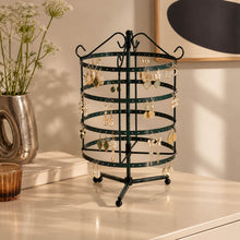 Charger l'image dans la galerie, Présentoir tourniquet noir garni de boucles d'oreilles dorées, posé sur une commode beige