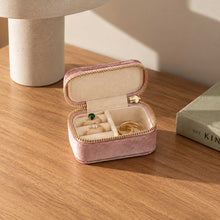 Charger l'image dans la galerie, Mini trousse à bijoux rose ouverte avec bagues dorées, posée sur une console en bois
